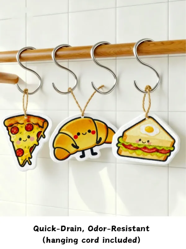 Pizza, croissant, and sandwich cellulose sponges hanging to dry with cords on white hooks.